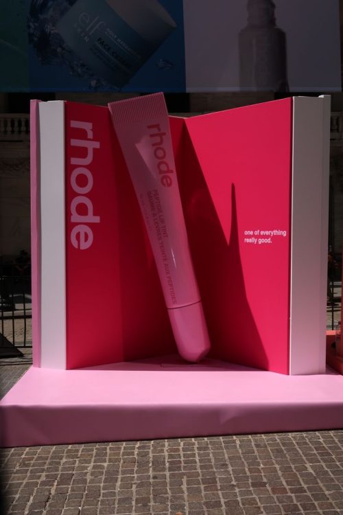 Giant pink lip tint replica sculpture displayed on a custom platform